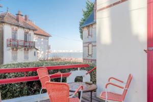 een rode bank en 2 stoelen op een balkon bij Grande maison 19p vue mer au Pouliguen in Le Pouliguen