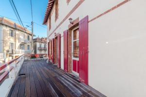 een houten terras met rode deuren op een gebouw bij Grande maison 19p vue mer au Pouliguen in Le Pouliguen