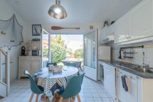 una cucina con tavolo e sedie e una cucina con finestra di Maison résidentielle à 200 m de la mer a La Bernerie-en-Retz