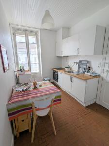 cocina con mesa y cocina con armarios blancos en T2 42 m² en Centre-ville de Cambo-les-Bains, en Cambo-les-Bains