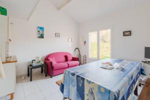 ein Wohnzimmer mit einem rosa Stuhl und einem Tisch in der Unterkunft Maison - Pornic centre avec piscine in Pornic