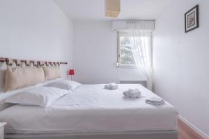 a white bedroom with a bed with two teddy bears on it at Appartement à 200m de ThalassoSpa in Pornic