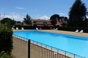 a large swimming pool with chairs and a fence at Maison en résidence proche du vieux port in Pornic