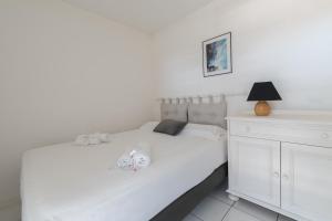a white bedroom with a white bed and a lamp at Appartement avec Golf tennis et mer in Pornic