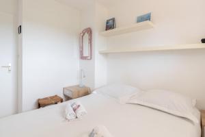 ein Schlafzimmer mit einem weißen Bett und zwei Hausschuhen darauf in der Unterkunft Appartement vue sur Golf de Pornic in Pornic