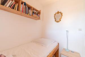 ein kleines Schlafzimmer mit einem Bett und einem Spiegel in der Unterkunft Appartement vue sur Golf de Pornic in Pornic