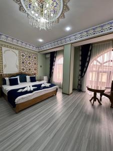 a bedroom with a large bed and a chandelier at Hotel Zarhal in Bukhara