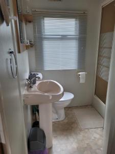 a white bathroom with a toilet and a sink at 6 Berth on Sealands Ingoldmells (Torino II) in Ingoldmells