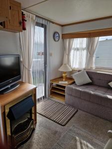 a living room with a couch and a television at 6 Berth on Sealands Ingoldmells (Torino II) in Ingoldmells