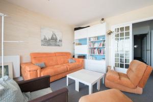 uma sala de estar com um sofá laranja e cadeiras em LE LITTORAL - Plage Bonne-Source em Pornichet