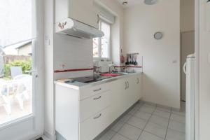 a white kitchen with a sink and a window at Birochère Maison lumineuse avec jardin in Pornic