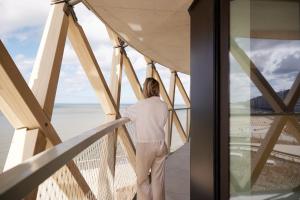 a woman standing on a balcony looking out at the ocean at C-Hotels Silt in Middelkerke