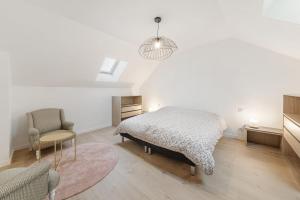 1 dormitorio blanco con 1 cama y 1 silla en La Roselière, en Dol-de-Bretagne
