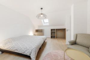 1 dormitorio blanco con 1 cama y 1 silla en La Roselière, en Dol-de-Bretagne