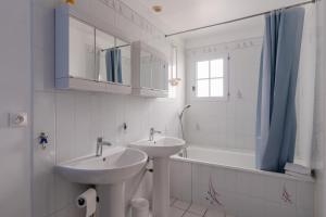 een badkamer met 2 wastafels, een bad en een raam bij Maison familiale avec jardin in Pornic