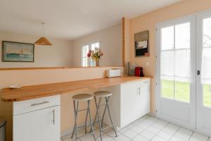 een keuken met witte kasten en een aanrecht met krukken bij Maison familiale avec jardin in Pornic