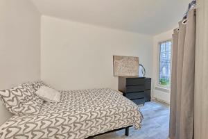 a bedroom with a bed and a dresser and a window at L'Augustine - Appartement dans le 15e in Paris