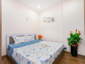 Dormitorio con cama con edredón azul y planta en GOLD SEA Vung Tau Apartment -Tina en Vung Tau