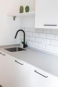 a white kitchen with a sink and white tiles at Resolana Suites in Seville