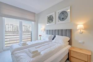 two beds in a bedroom with a large window at Scala Apartments by Blue Mandarin in Gdańsk
