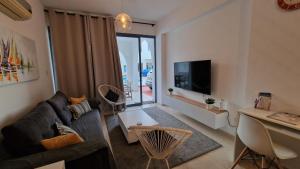 sala de estar con sofá y TV en Blue Pearl holiday apartments with pool in kato paphos, en Pafos