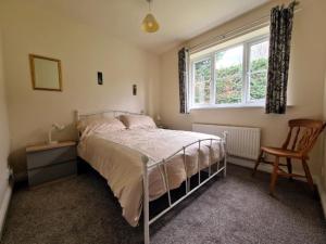 una camera da letto con un letto, una sedia e una finestra di Elderflower Cottage a Stamford