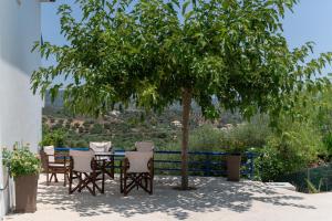 a table and chairs under a tree in a yard at Blue Houses Maisonettes in Kamária