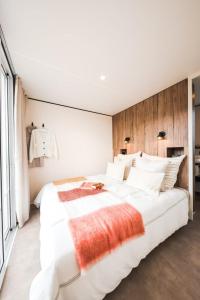 um quarto com uma grande cama branca e uma cabeceira em madeira em Camping Golfo Di Sogno em Porto-Vecchio