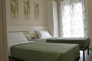 two beds in a room with a window at Green and Blue Apartment in Rome
