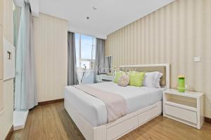 a bedroom with a large white bed and a window at Sepia By Kozystay - MACAN Museum - Kebon Jeruk in Jakarta