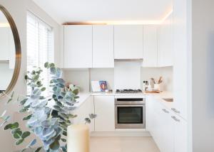 a white kitchen with white cabinets and a plant at Pond Place Apartments in London