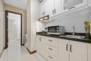 a white kitchen with a sink and a microwave at Sepia By Kozystay - MACAN Museum - Kebon Jeruk in Jakarta