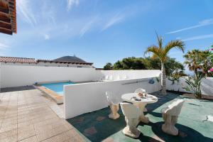 een patio met een tafel en stoelen en een zwembad bij Villa Duke in San Miguel de Abona