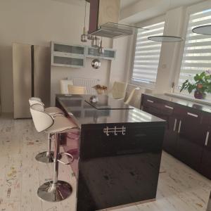 a kitchen with a black island and white chairs at Bordó apartmán A4 v Chomutově in Chomutov