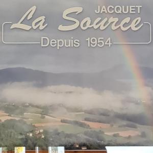 a rainbow in the sky over a city at LA SOURCE Jacquet depuis 1954 Hôtel et Studio in Saint-Jean-de-Chevelu