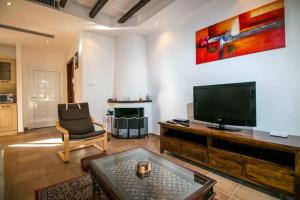 a living room with a flat screen tv and a chair at Villa Olympos Ladiko in Kalithies