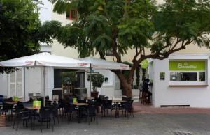 a restaurant with tables and chairs and a tree at Be Happy Hostel in Nerja