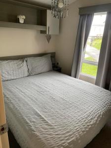 um quarto com uma cama branca e uma janela em Littlesea Haven fleetview em Weymouth