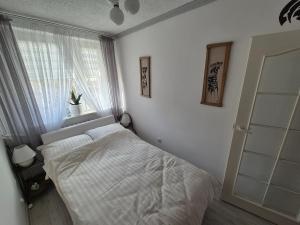 a white bedroom with a bed and a window at Przytulny apartament blisko MOLO GIŻYCKO in Giżycko +1 photo