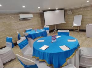 uma sala de conferências com mesas e cadeiras azuis e um ecrã em Hotel Airport inn plaza near delhi airport Aerocity em Nova Deli