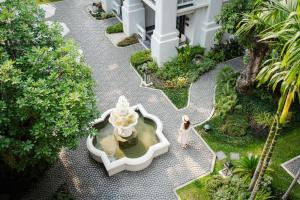 Una mujer caminando alrededor de una fuente en un patio en Buri Sriping Riverside Resort & Spa - SHA Extra Plus, en Chiang Mai