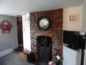 a stone fireplace with a mirror on top of it at Langdon Farm Cottage in Boyton