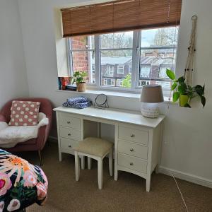 einen Schreibtisch in einem Zimmer mit einem Fenster und einem Stuhl in der Unterkunft Alexandra Park in Manchester