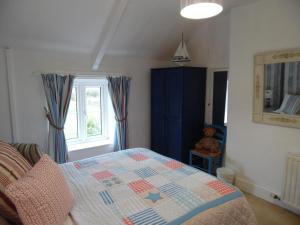 a bedroom with a bed with a quilt on it at Langdon Farm Cottage in Boyton