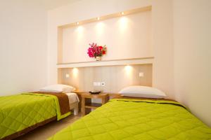 2 camas en una habitación con mantas verdes y flores en Galaxy Hotel, en Mylopotas