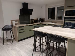 a kitchen with three bar stools and a counter at Du panier au gite in Vouziers