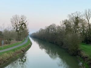 a river with trees and a road next to it at Du panier au gite in Vouziers