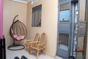 une paire de chaises et une balançoire sur une terrasse couverte dans l'établissement Kica Apartment with Airconditioned bedrooms in Lira, Uganda, à Lira