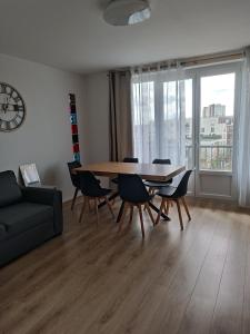 een woonkamer met een tafel en stoelen en een klok bij Appartement proche PARIS/STADE DE FRANCE in Épinay-sur-Seine