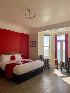 a bedroom with a large bed with a red wall at Lundy House Hotel in Woolacombe